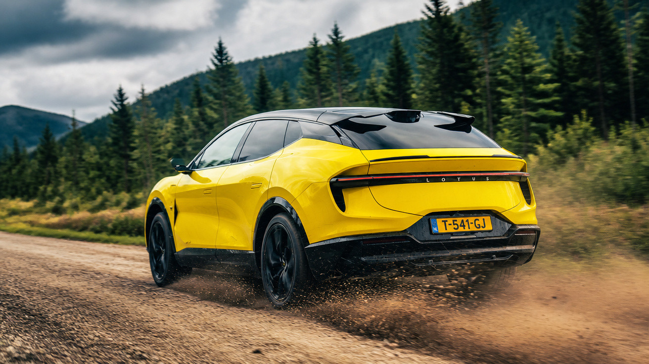 Carro elétrico amarelo Lotus em estrada de terra rodeada por árvores verdes e céu nublado.